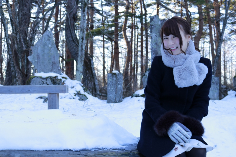 雪の積もるベンチで笑いかける女性のフリー写真素材 ニューファクトリー